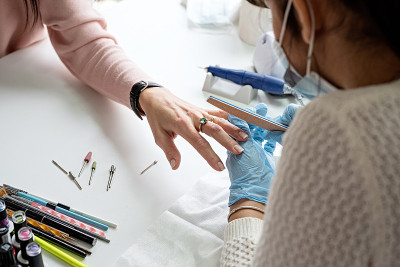 Manicure master in gloves using nail file to buff 