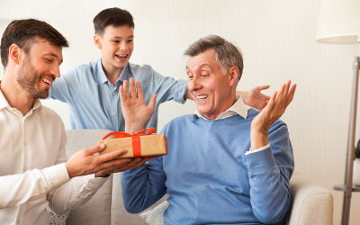 儿子和孙子祝贺坐在沙发上的老人