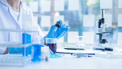 在实验室里观察透明溶液的试管的医学或科学研究者或男医生