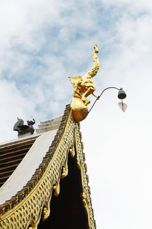 泰国佛教寺院的艺术屋顶上挂着金色的那伽和铃铛，天空湛蓝