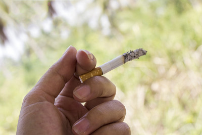木制背景上的手和香烟。成瘾概念