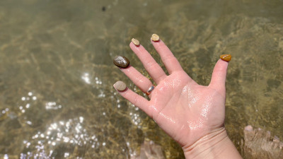 女人的手拿着海卵石，背景是海水