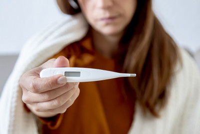 一个生病的女人躺在沙发上检查体温