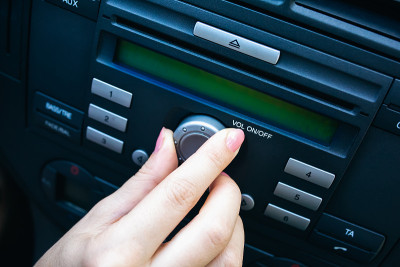一个女人正在打开车上的收音机音量。女孩开车。