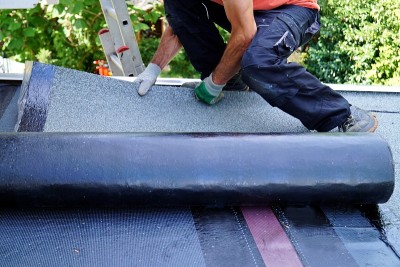 工人正在建筑屋顶上安装焦油箔。平屋顶安装。气、火点火防水系统。