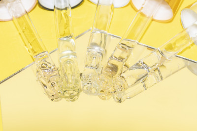 装有血清、透明质酸和维生素的不同吸管滴管，置于黄色背景的镜子上