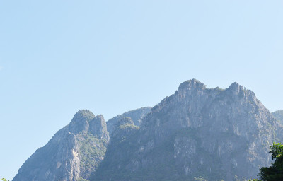 石灰岩山上的岩壁和绿色森林，蓝天白云为背景