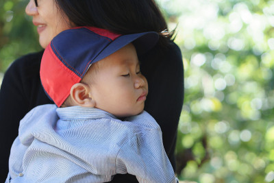 熟睡的亚洲婴儿被他的母亲抱着