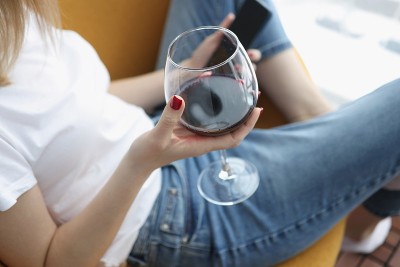 女人手里拿着智能手机和一杯葡萄酒