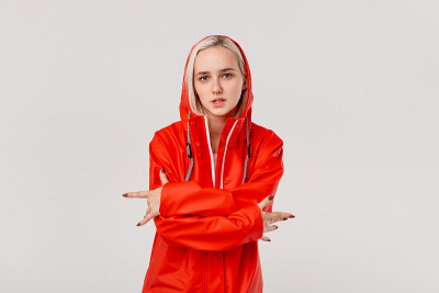 金发女孩穿着红色雨衣带着兜帽跳舞享受生活即使在寒冷的天气。你准备好迎接寒冷的坏天气了吗?