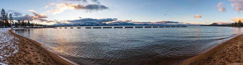 日落在南太浩湖的海岸线上，塞拉山的山峰覆盖在雪中可见的背景，加利福尼亚州