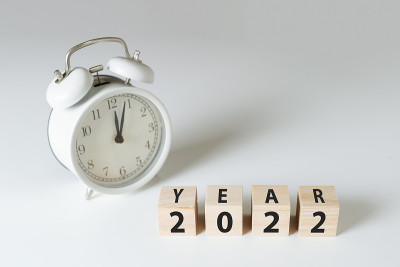 白色桌子上有字2022的木块立方体，闹钟时间为00点04分。新的2022概念。