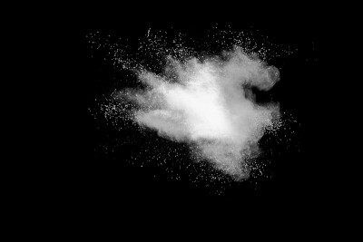 白色粉末爆炸云在黑色背景下。白色灰尘颗粒飞溅。