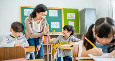 小学生在小学教室里与老师击掌。在小学学习的男生。孩子们在教室里写笔记。教育知识，成功团队理念