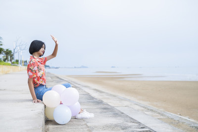 亚洲年轻女孩喜欢在海滩上玩气球。