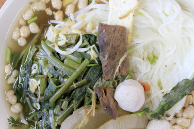 在素食节的木桌上，白碗里放着萝卜、牵牛花、香菇和豆腐。