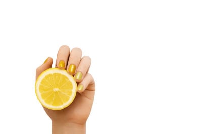 黄色的指甲的设计。女性的手与闪光美甲握柠檬