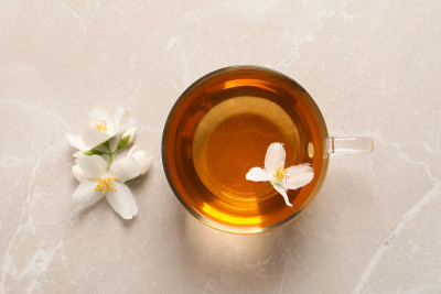 灰色的桌子上放着一杯香喷喷的茉莉花茶和鲜花