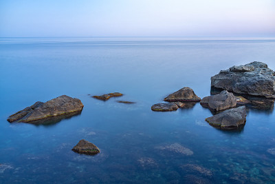 暮色笼罩着荒凉的岩石海滩、海岸线和大海。大海和岩石在夜间的广角视野。