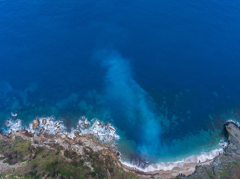 航拍从无人机一个惊人的自然风景与岩石海岸和海浪。清澈的绿松石水面下的白色斑点。