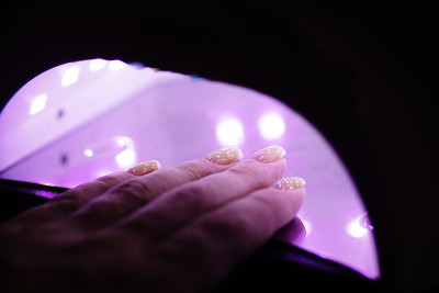 紫外线灯凝胶抛光美甲工艺在美容院。沙龙的过程。师傅给客户的指甲涂上清漆。有选择性的重点