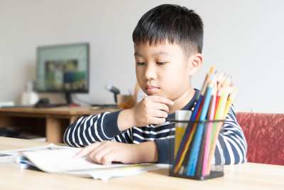 亚洲男孩在小学读书，自己在家做作业。