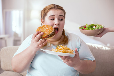 超重的年轻女性正在思考她不健康的饮食习惯