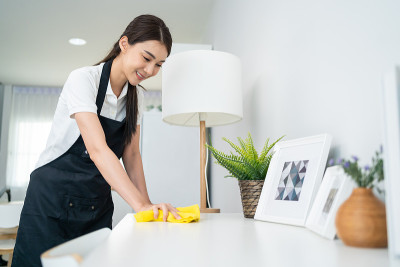 亚洲清洁服务女工清洁客厅在家里。美丽的女孩主妇管家清洁工感到高兴，并擦拭脏乱的工作台面为家政家务或杂