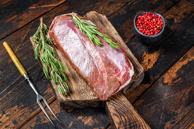生鲜鸭肉胸肉排配香草和迷迭香。深色木制背景。俯视图