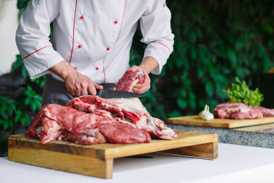 在餐馆里，一个厨师用刀切肉