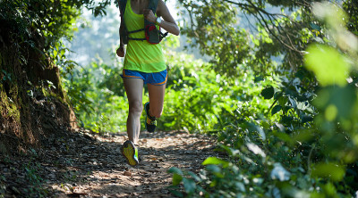 Woman ultra marathon runner running on forest trai