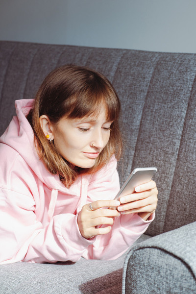 年轻女子在沙发上玩手机。