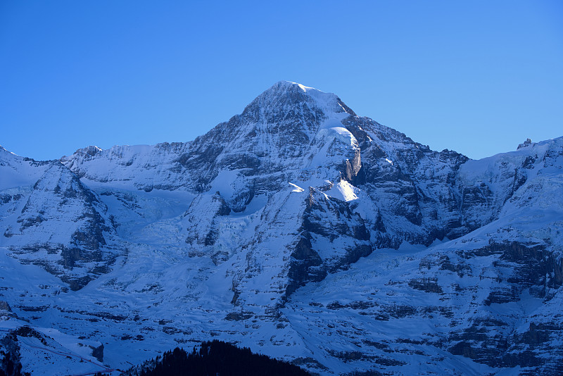 在阳光明媚的冬日，从Winteregg Mürren可以看到瑞士阿尔卑斯山脉的蒙克峰和冰川的美丽山景