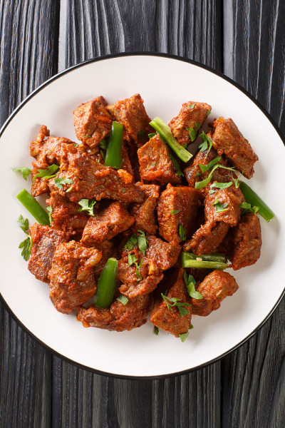 Tibs是一种很受欢迎的埃塞俄比亚菜sautéed牛肉调味的硝基羊肉和柏柏尔在盘子里的特写。垂直的俯