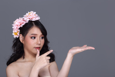 漂亮的亚洲年轻女子与花冠，目前空手掌