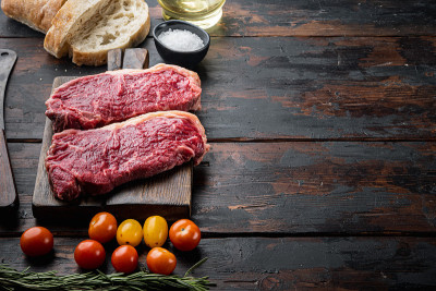 牛排汉堡配料与牛肉大理石肉，在深色的木制背景，与文本复制空间