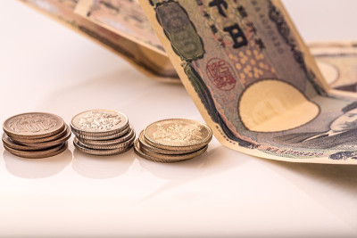 白色的桌子上放着日本的硬币、钞票和护照