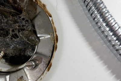 头发放在淋浴排水虹吸管里。许多毛发造成了管道堵塞和水的损坏。特写镜头