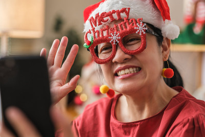 亚洲妇女戴圣诞帽视频电话聚会与朋友与移动电话桌上在家里