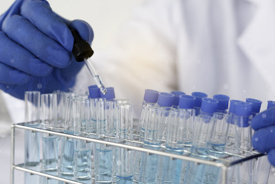 生物化学实验室研究，科学家或医务人员在实验室工作的玻璃设备上，穿着实验室大褂，拿着带有彩色液体的使用