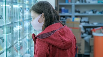 戴着防毒面具的妇女在商店里挑选电子产品