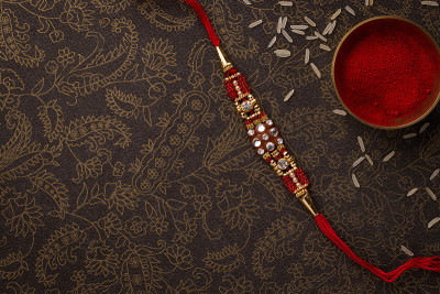 Raksha Bandhan背景与优雅的Rakhi和米粒深色纹理背景。
