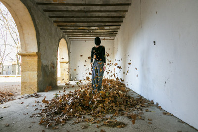 woman with hat throwing dry leaves in the air