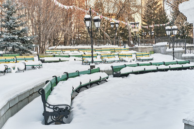 城市公园夏季露天剧场里的白雪覆盖的木凳。