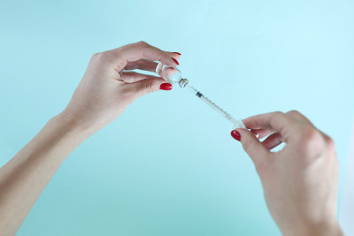 女性的手正用注射器从瓶子里取药