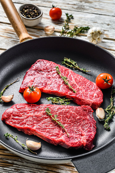 平底锅里的生丹佛牛排。有机牛肉肉。白色木制背景。俯视图