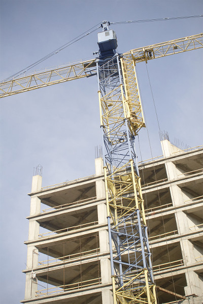 一座未完工的建筑和一台黄色的起重机。未完成建设。