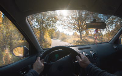 在秋天的森林里，一个男人在一条森林道路上开车。的观点。