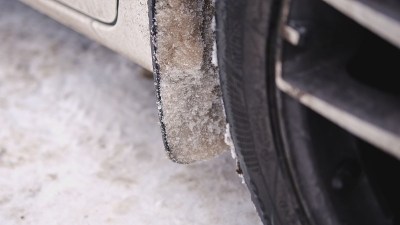 车轮上的泥板上收集了大量的冰冻雪泥