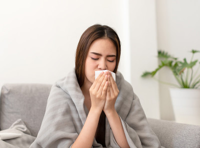 亚洲年轻女子生病，不适，感冒和有流感症状在沙发上。